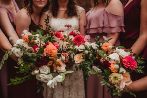 Close up of coorful bouquets, held by a bride in white and women in varying shades of mauve.