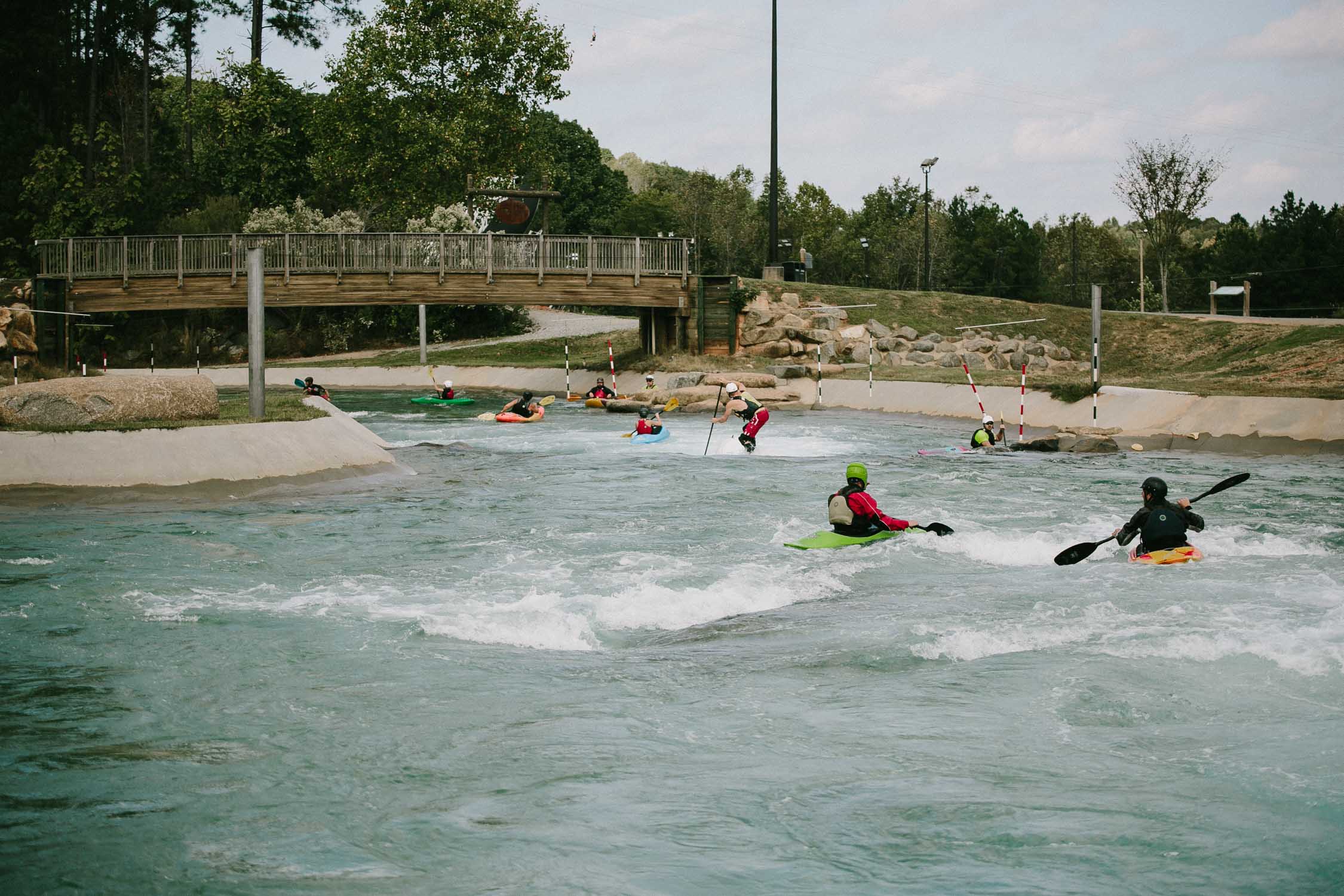 US National Whitewater Center, view of the river with people kayaking and paddle boarding.