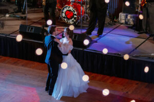 A bride and groom dance under market lights. We view from above, looking through the lights.