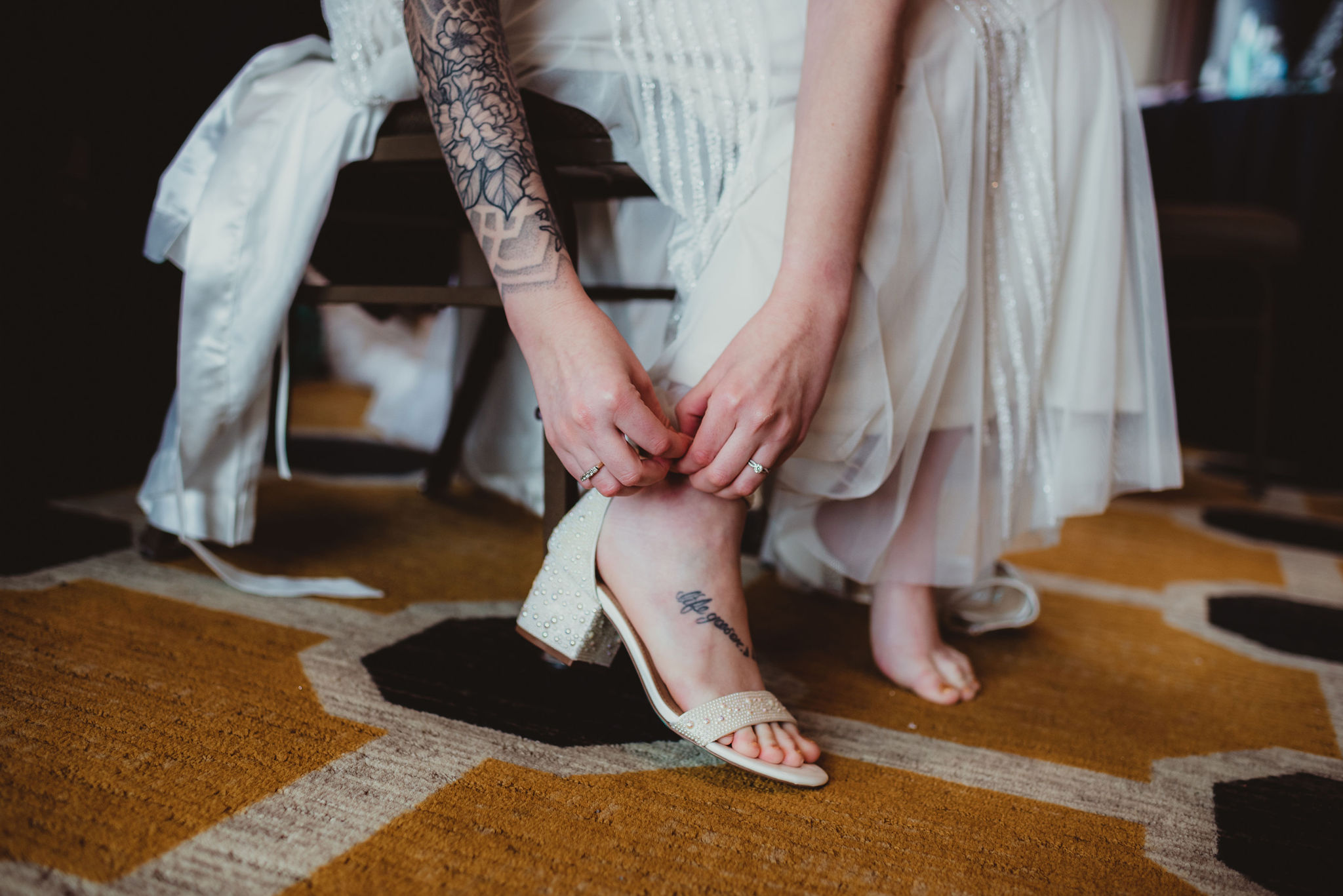 Close up on a white bride strapping on her white heels. 