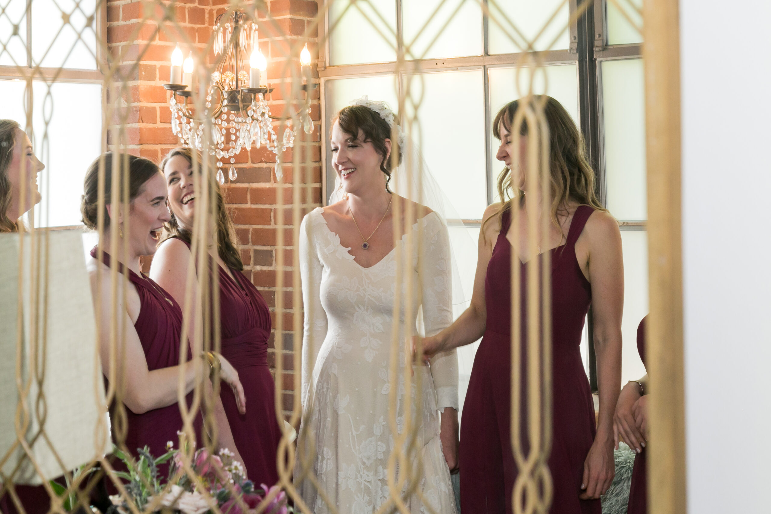 A reflection in a mirror shows a bride laughing with her bridesmaids.